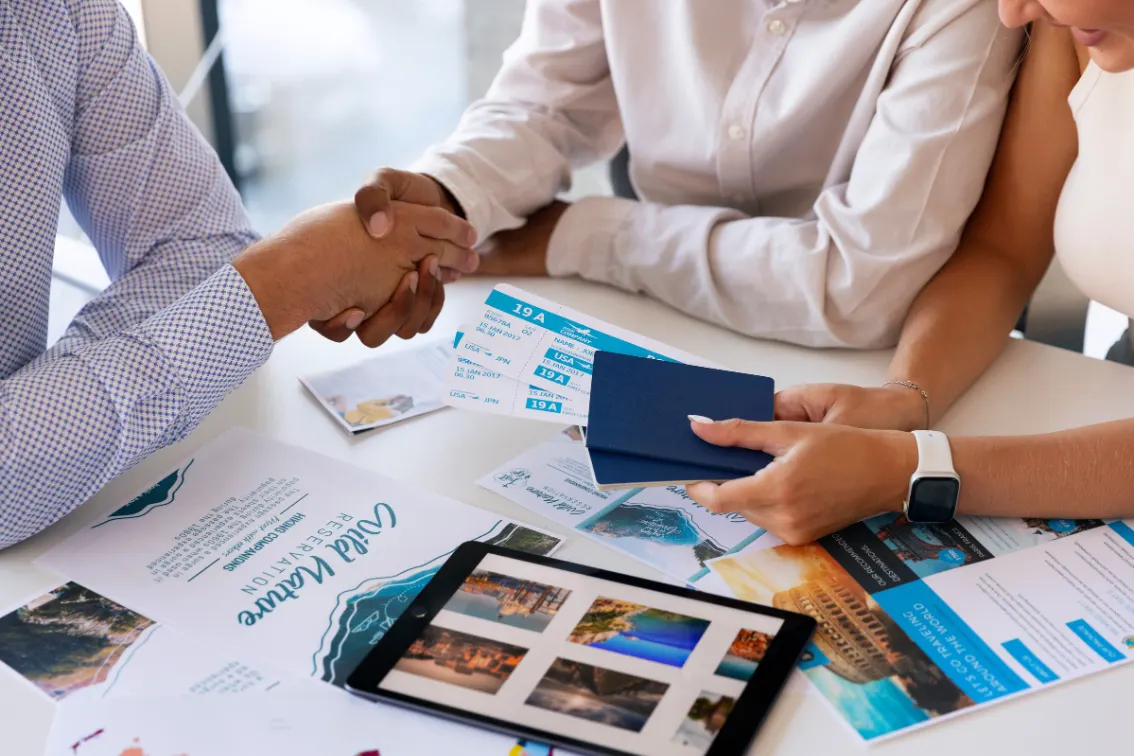 Business partners shaking hands over travel plans and a tablet
