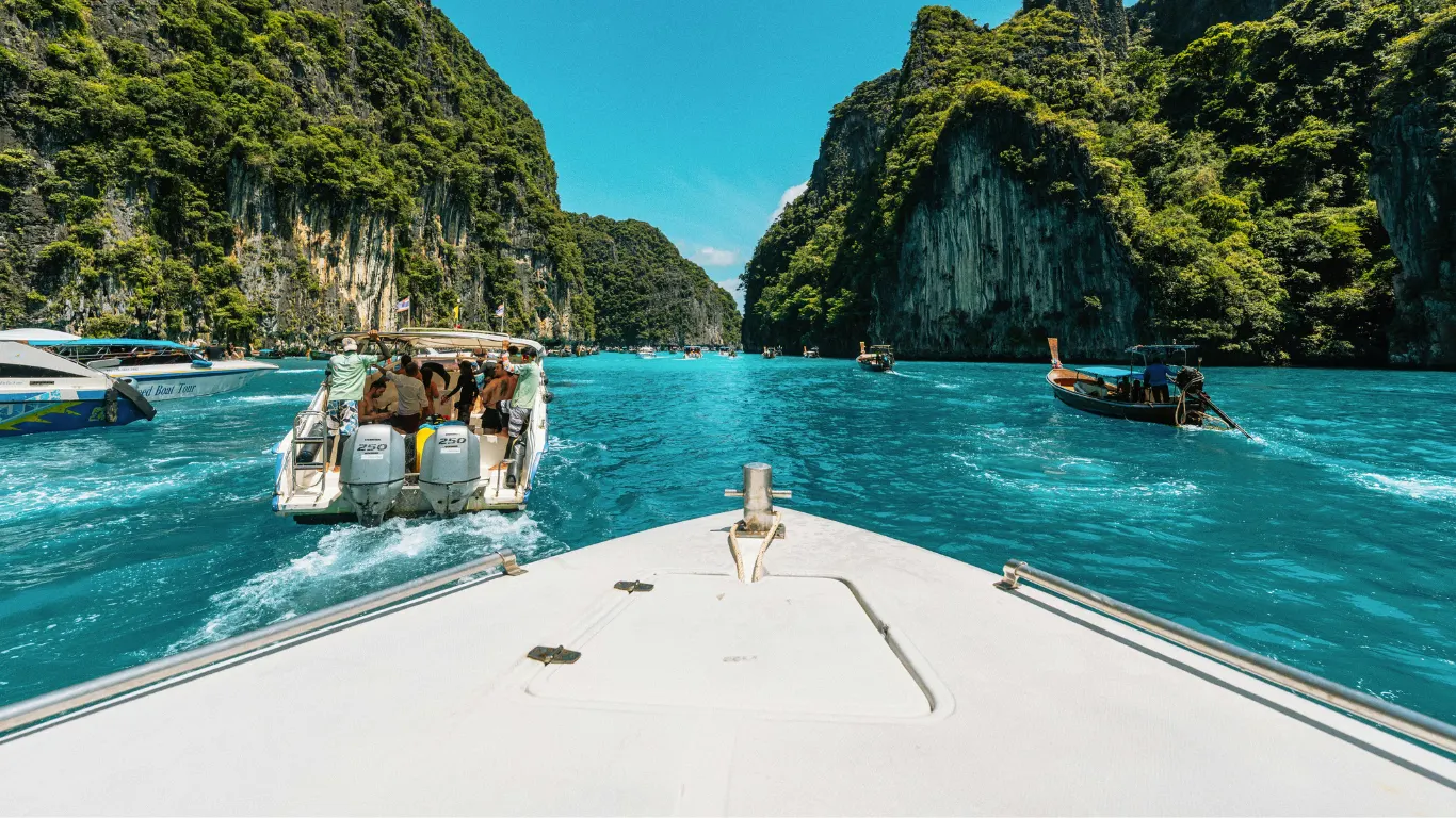 Boat cruising through turquoise water between limestone cliffs